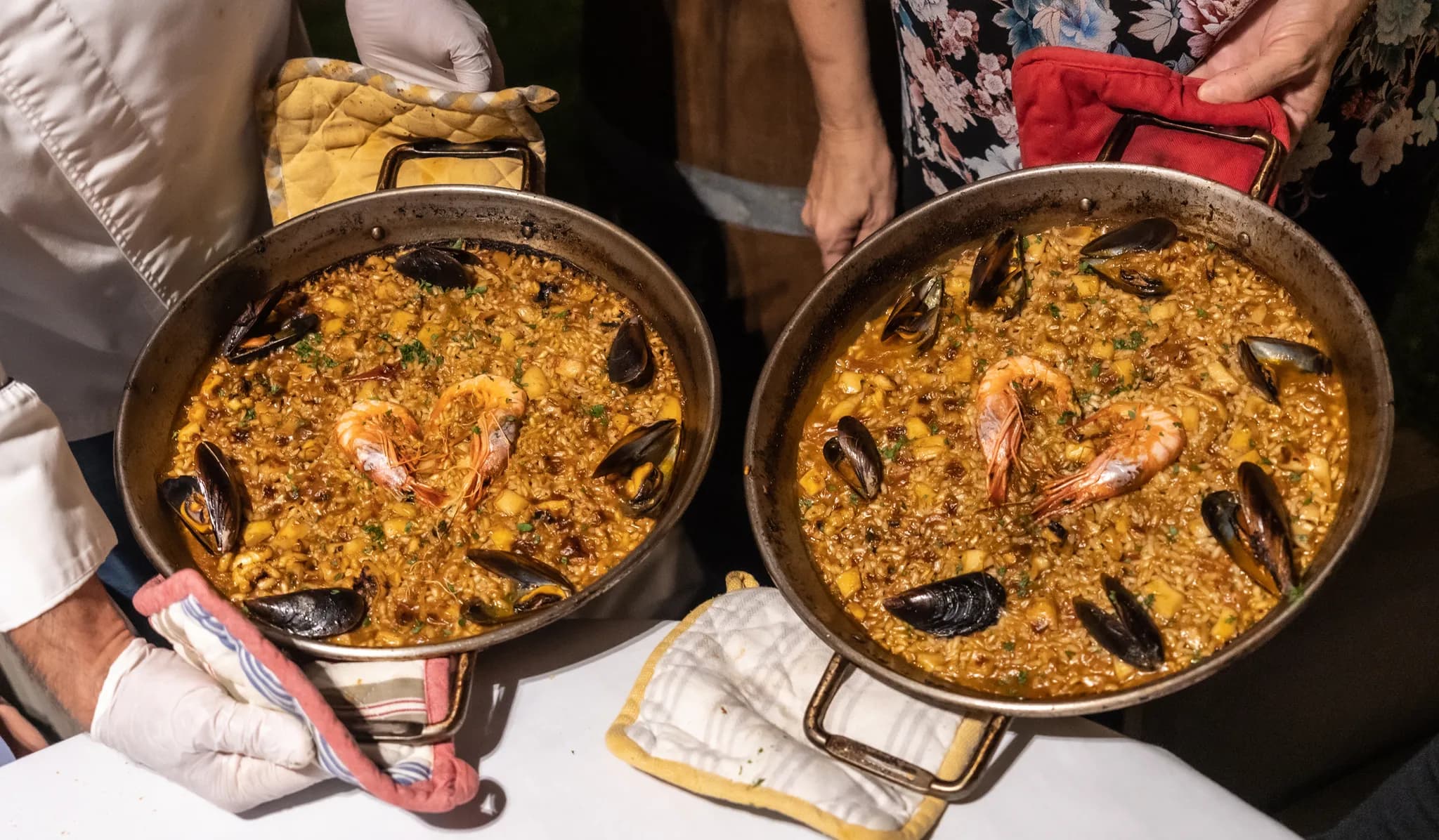 Deux cuisiniers présentent deux paellas aux fruits de mer tout juste préparées