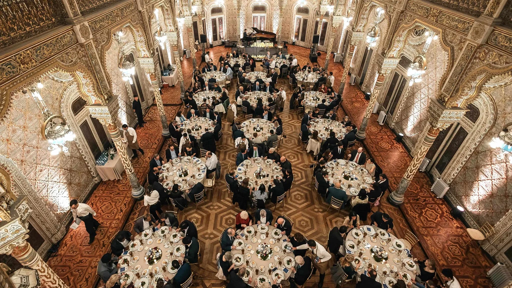 Dîner de gala dans une salle ornée de style mauresque, avec des invités assis à des tables rondes sous des lustres
