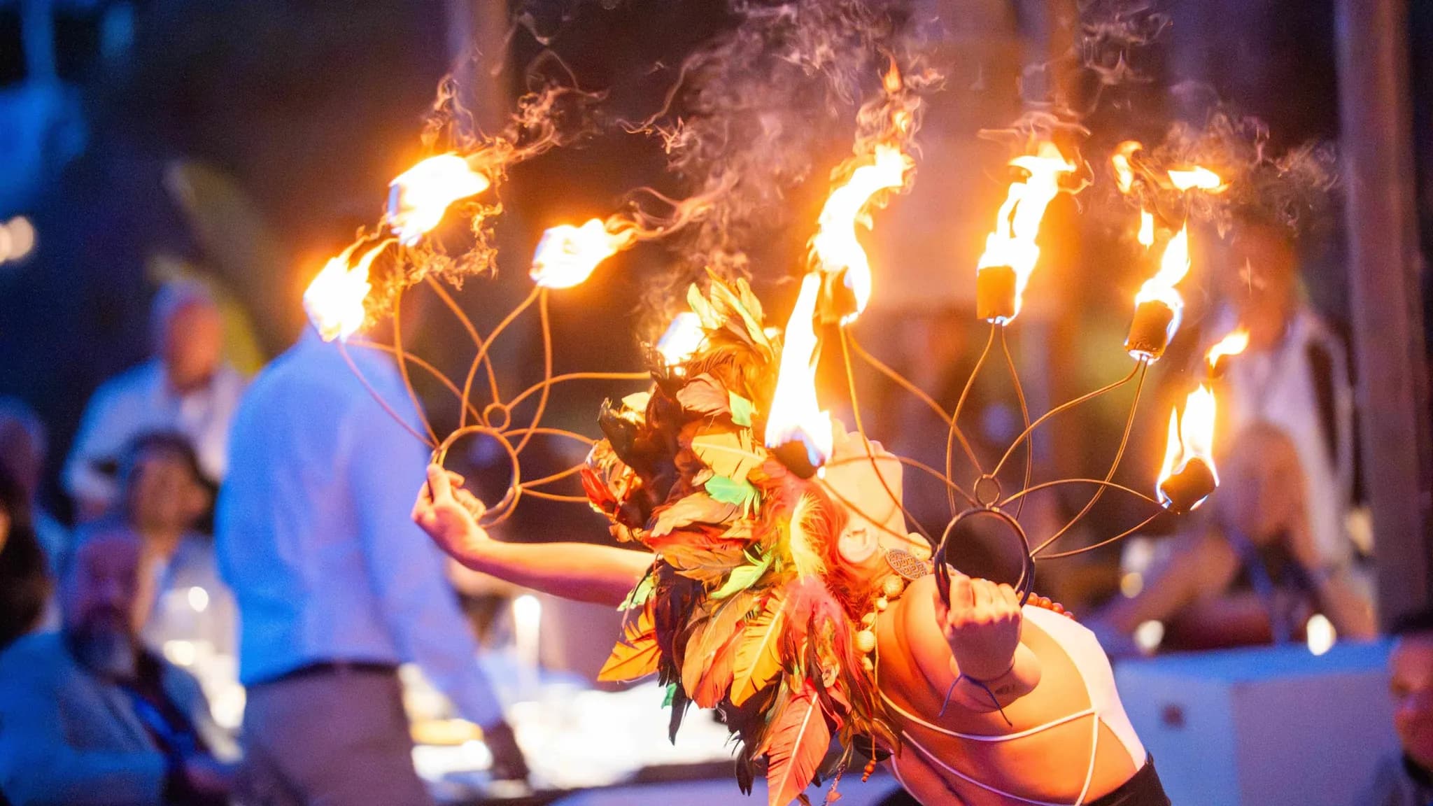 Un artiste de feu en costume de feuillage et coiffe enflammée divertissant les invités lors d'une soirée